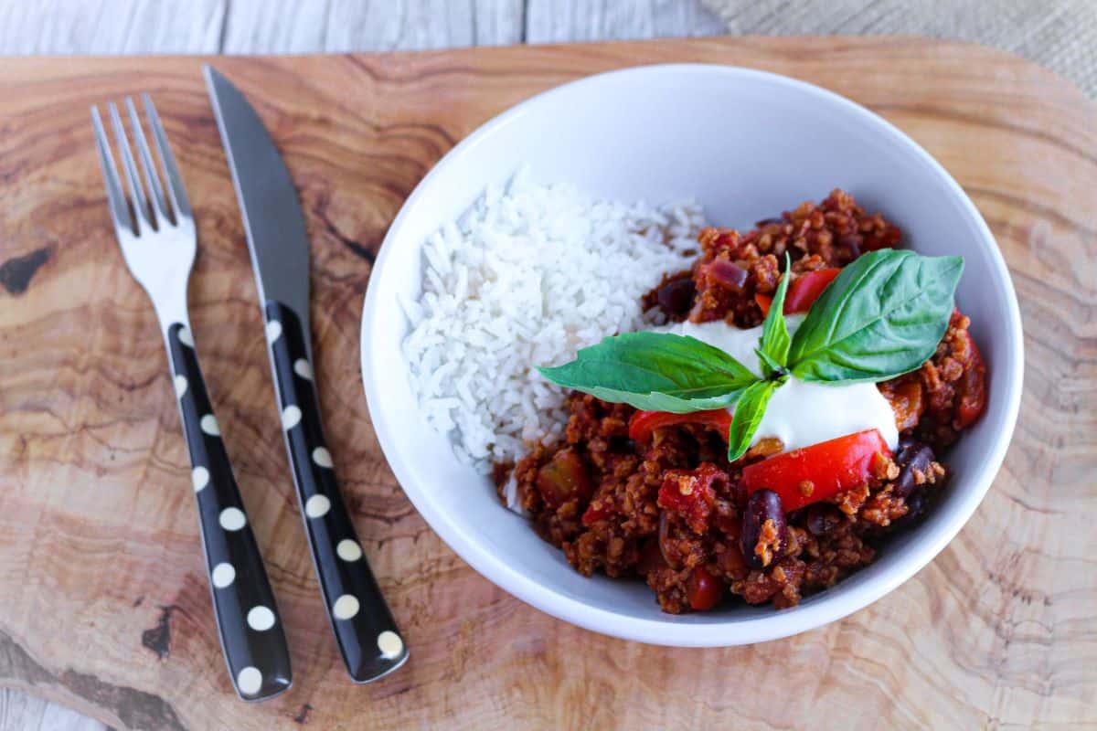 5 Minute One Pot Vegan Chili with a knife & fork on a board.