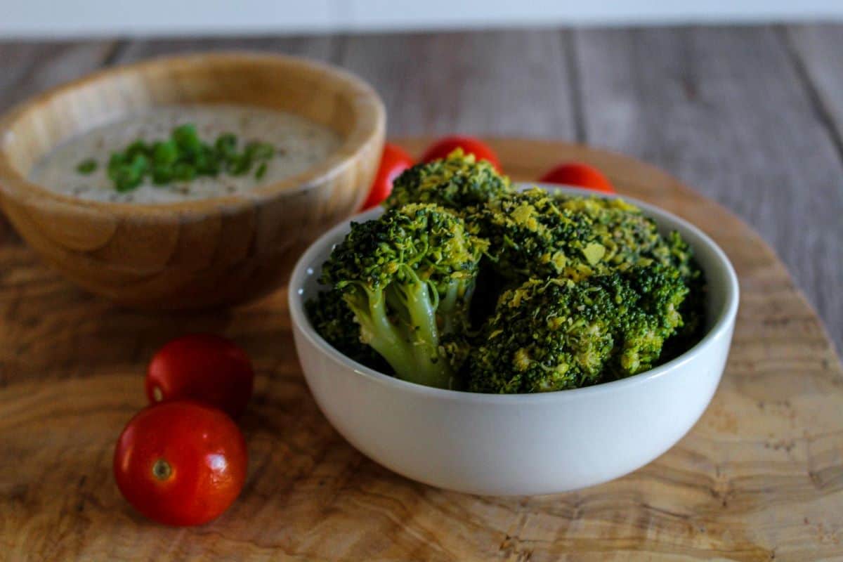 Easy Vegan Cheesy Broccoli in a bowl with tomatoes on the side.