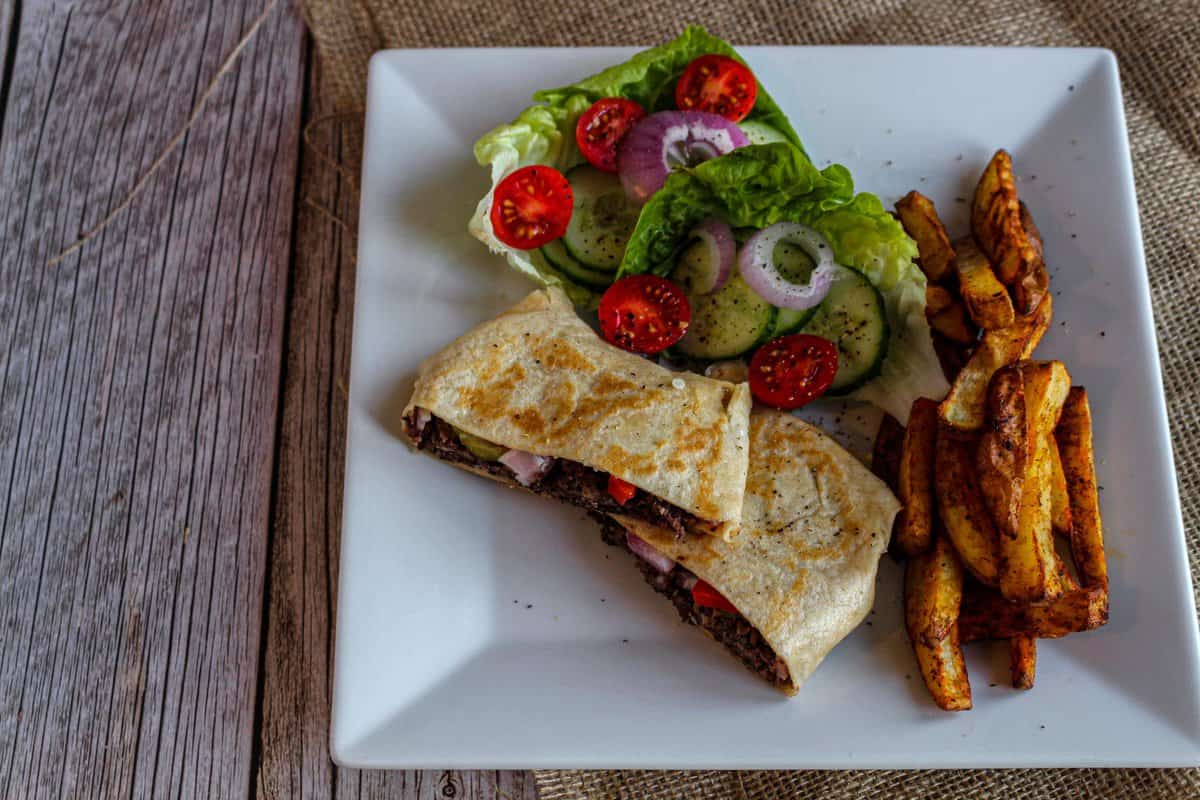 Baked Potato Fries on a plate with a vegan crunch wrap and a side salad.